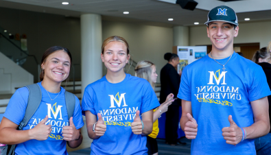 Three students in Madonna University shirts smile for the camera at 取向