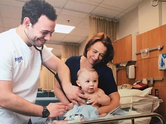 Nursing student checking heart of baby in sim lab